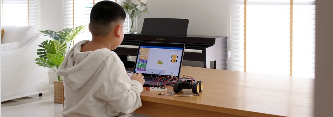 PCでロボットプログラミングをする子供